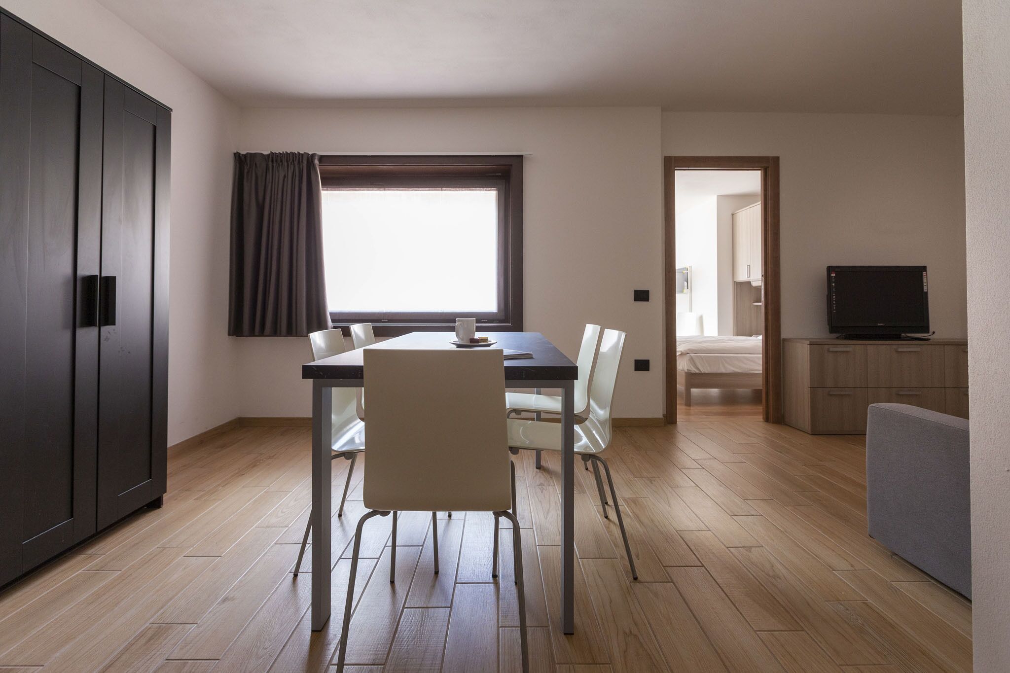 A compact living space with a dining area, a TV, and a kitchenette.