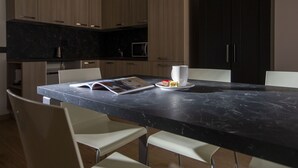 A modern kitchen with a marble countertop, white chairs, and a dining table. - Residence Adele (Livigno)