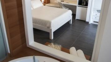 A modern bedroom with a large bed, a desk, and a walk-in closet.
