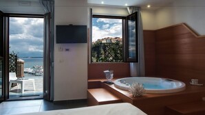 A modern hotel room with a large window, a bathtub, and a balcony with outdoor furniture. - La Sciabica (Agropoli)