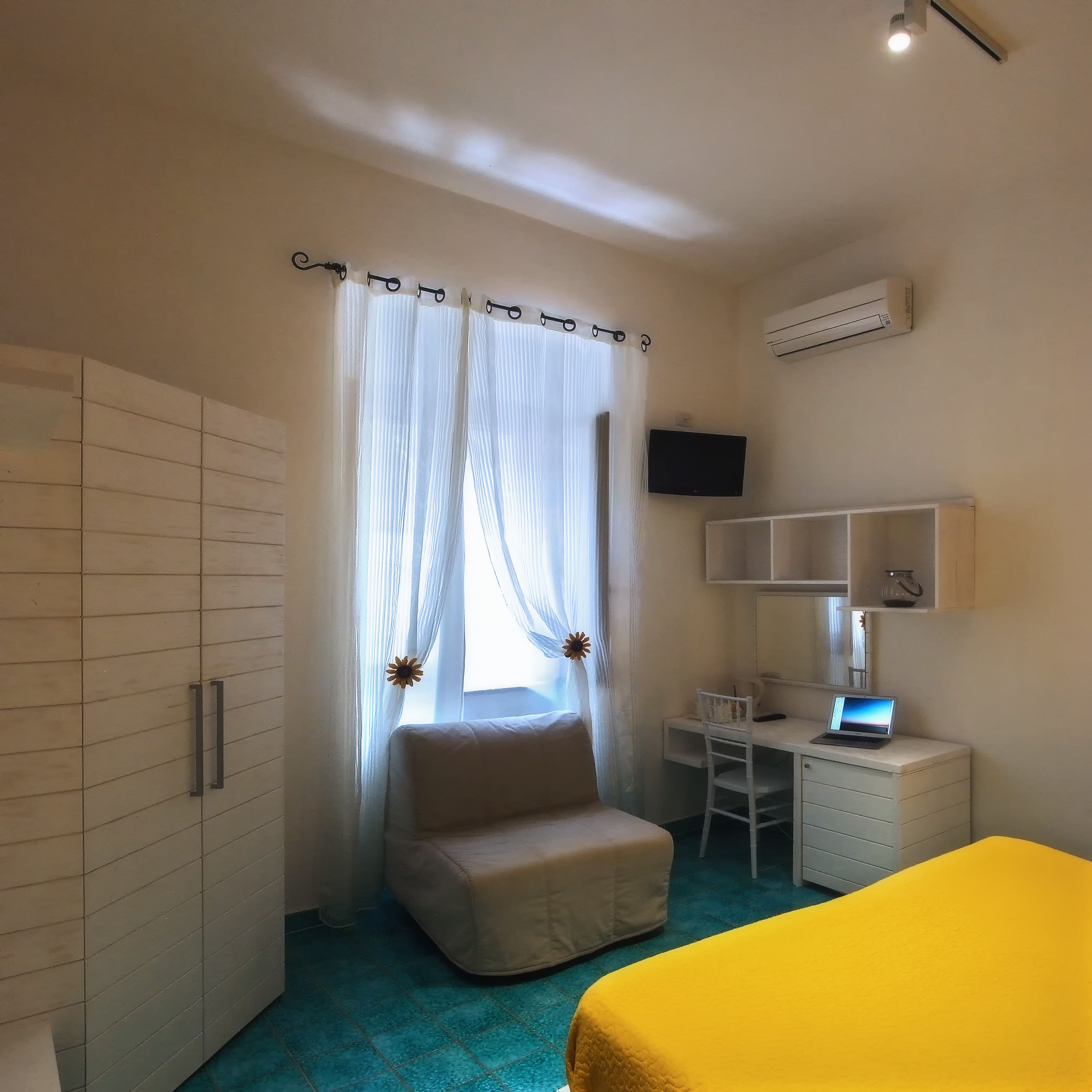 Un dormitorio con cama, escritorio, silla, armario y televisión.
