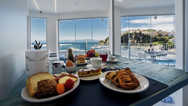 A breakfast table with various foods and a view of the sea and buildings. - La Sciabica (Agropoli)