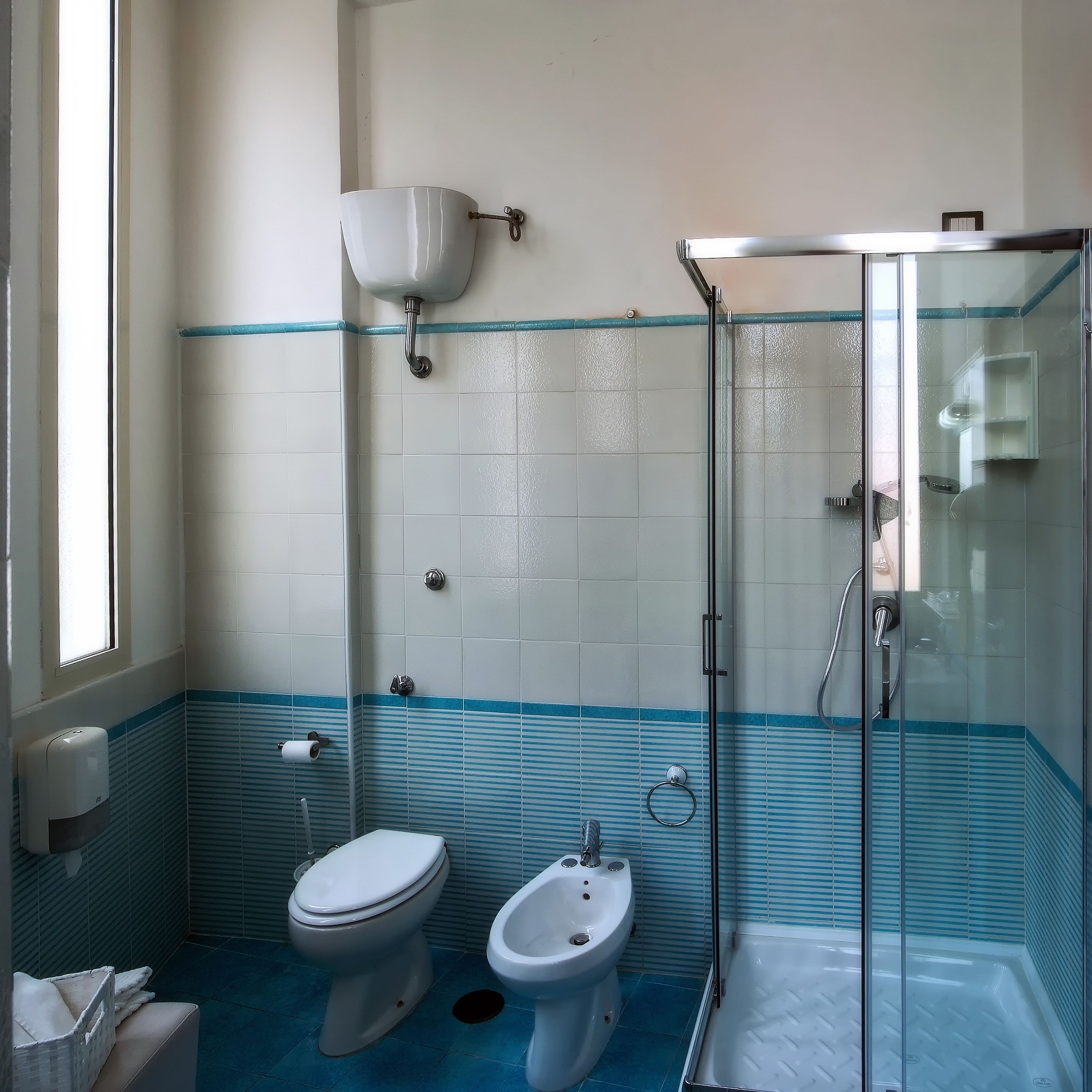 Un baño con inodoro, bidé y ducha con mampara de vidrio.
