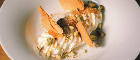 Un postre con crema batida, nueces y un trozo de pastel sobre un plato blanco.