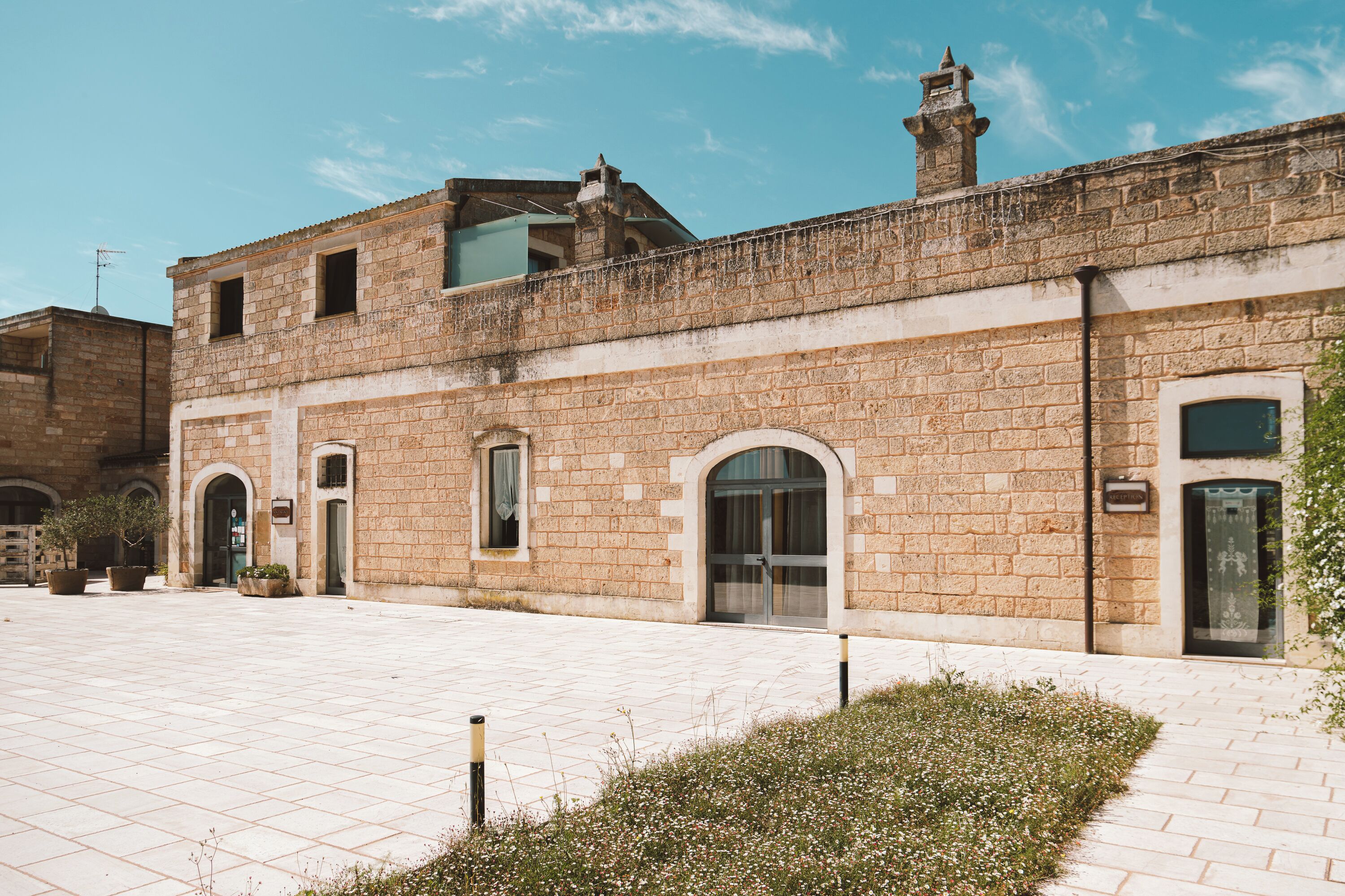 Ein historisches Gebäude mit Innenhof, mit einer Stein-Fassade, Rundbogenportalen und einer kleinen Gartenanlage.