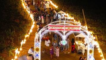 A nighttime outdoor event with a decorated archway and people gathered around.