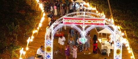 A nighttime outdoor event with a decorated archway and people gathered around.