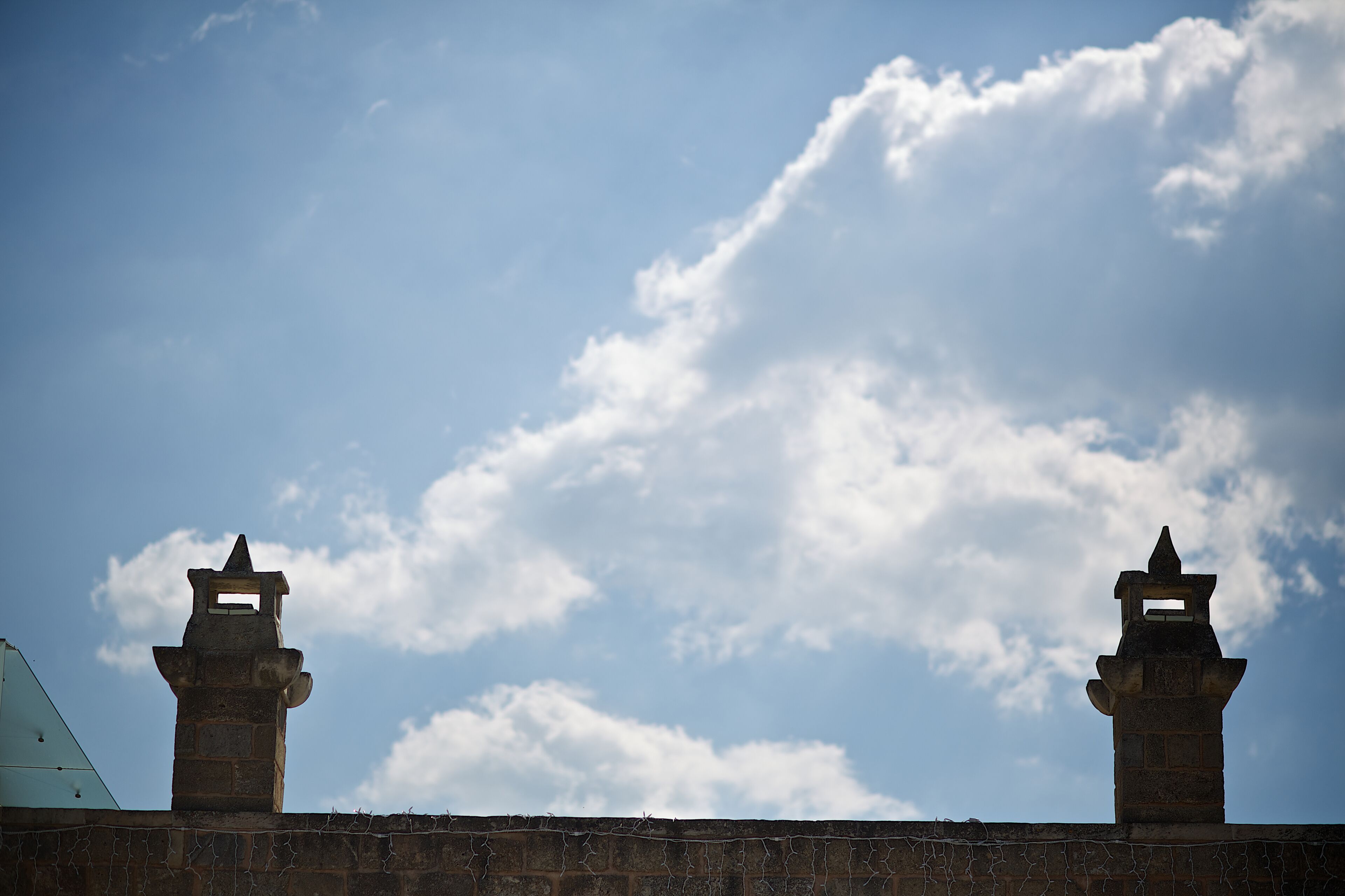 A stone wall with two towers against a partly cloudy sky.