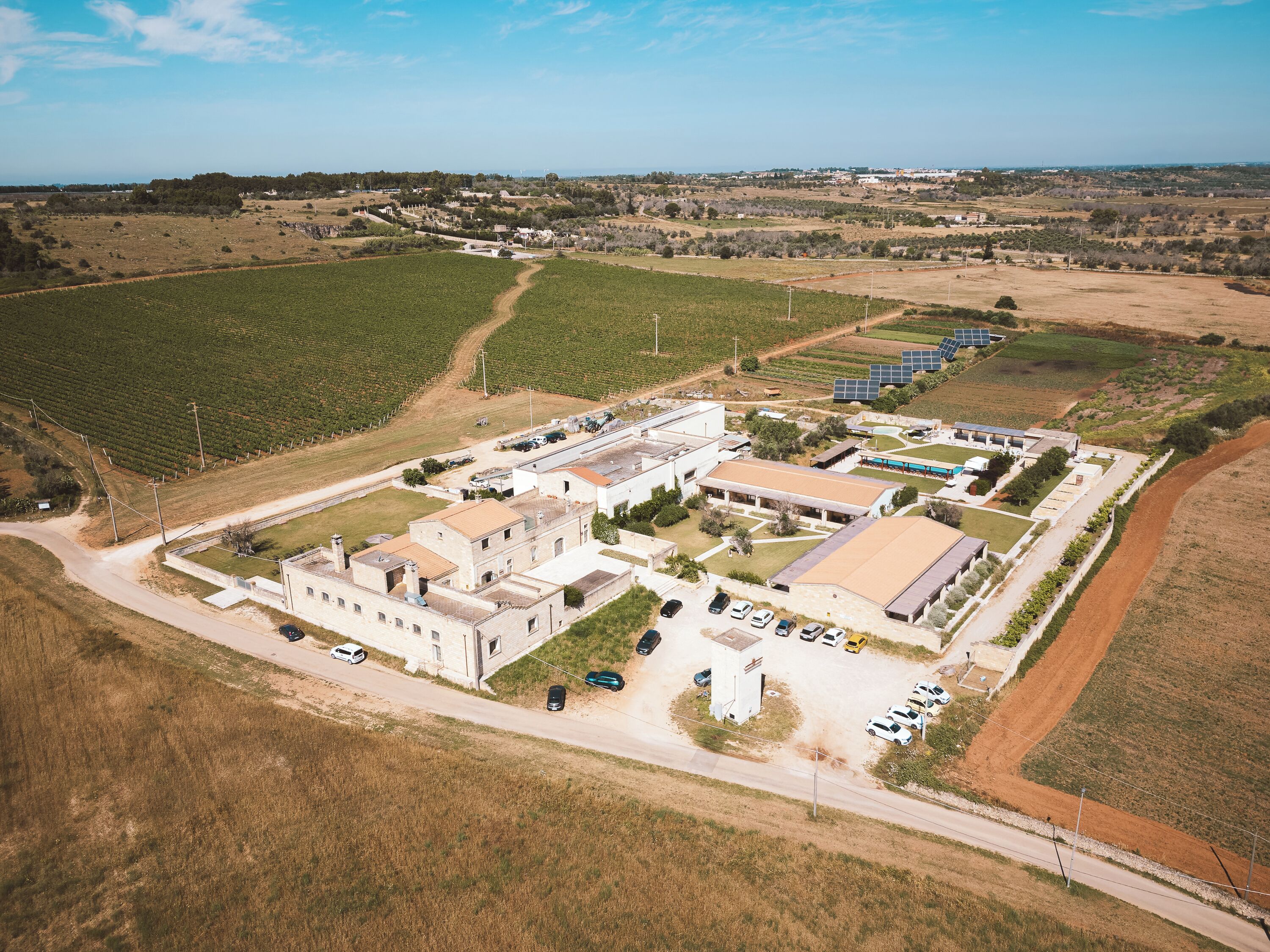 Vista aérea de un extenso complejo industrial con varios edificios, zonas de estacionamiento y paneles solares.