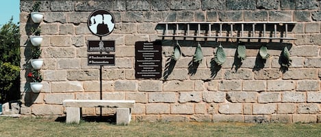 A stone wall with a bench, potted plants, and informational signs.