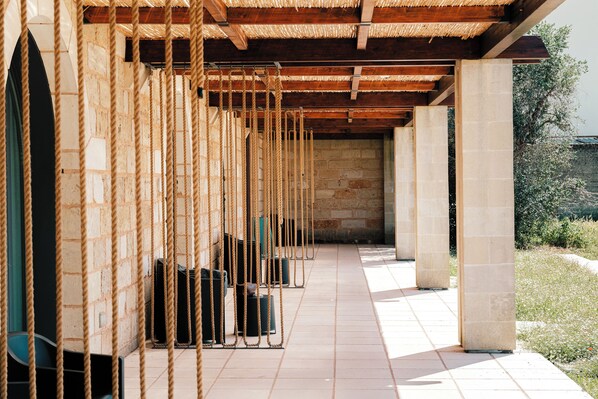 Un espacio al aire libre cubierto, con pared de ladrillo, vigas de madera y cuerdas.