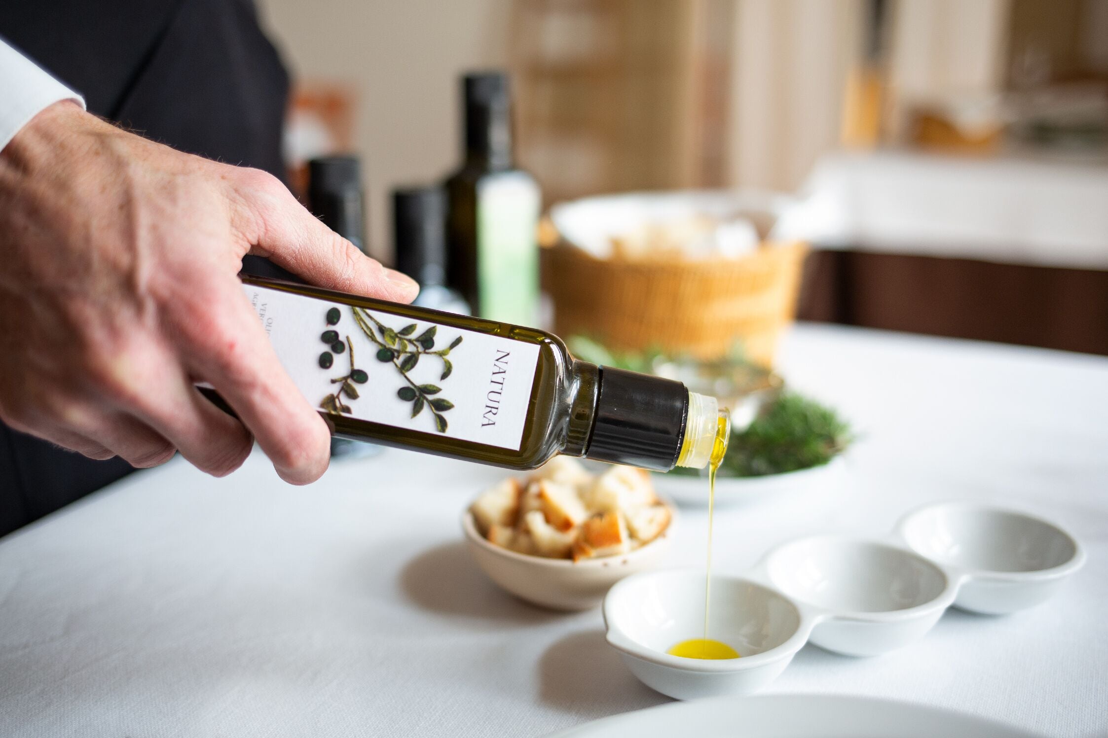 A person pouring olive oil into a bowl.