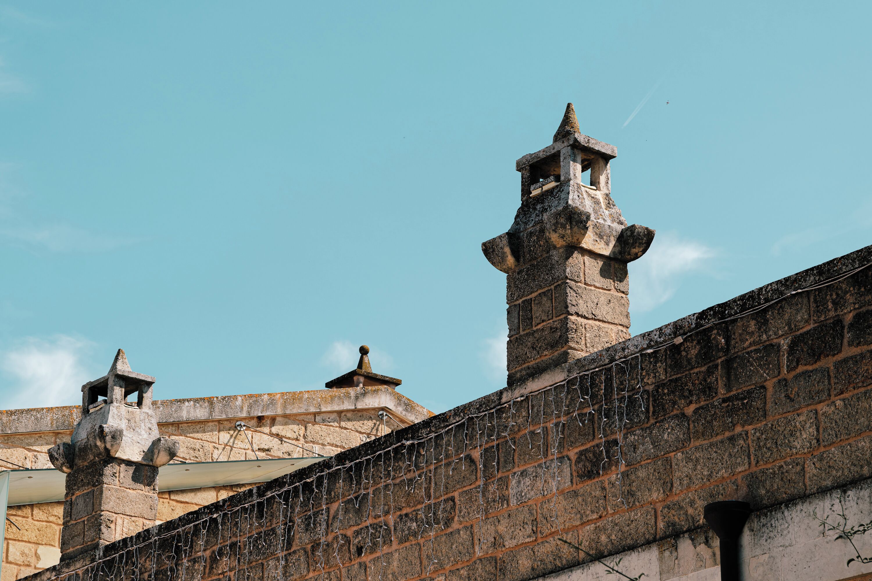 Un edificio de piedra con un muro de ladrillo y una valla metálica.