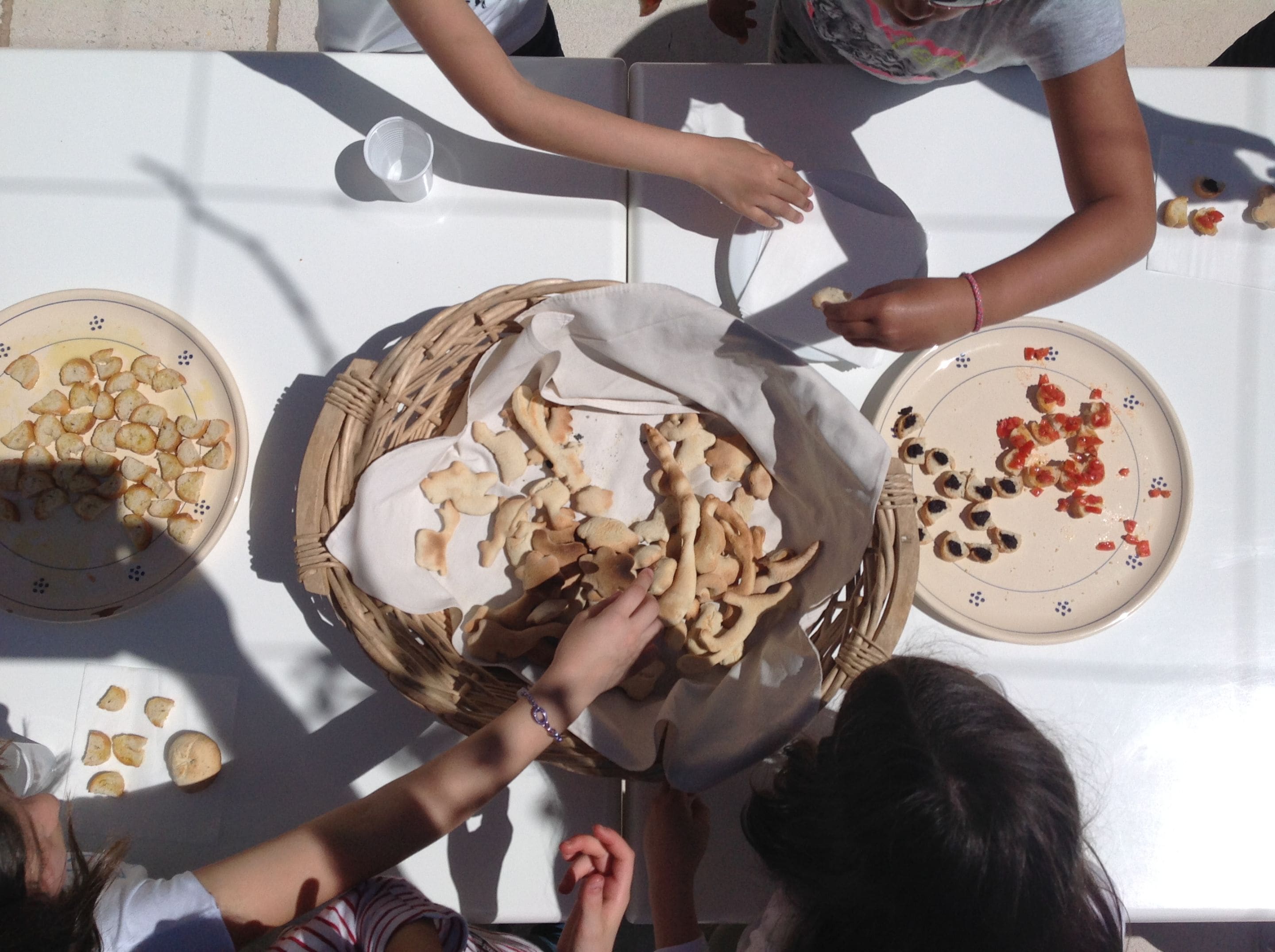 Une table avec des assiettes de nourriture, un panier et un gobelet en plastique.