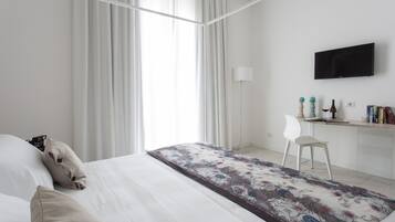 Ein modernes Hotelzimmer mit einem großen Bett, einem Schreibtisch, einem Stuhl, einem Fernseher und einem Fenster mit Vorhängen.