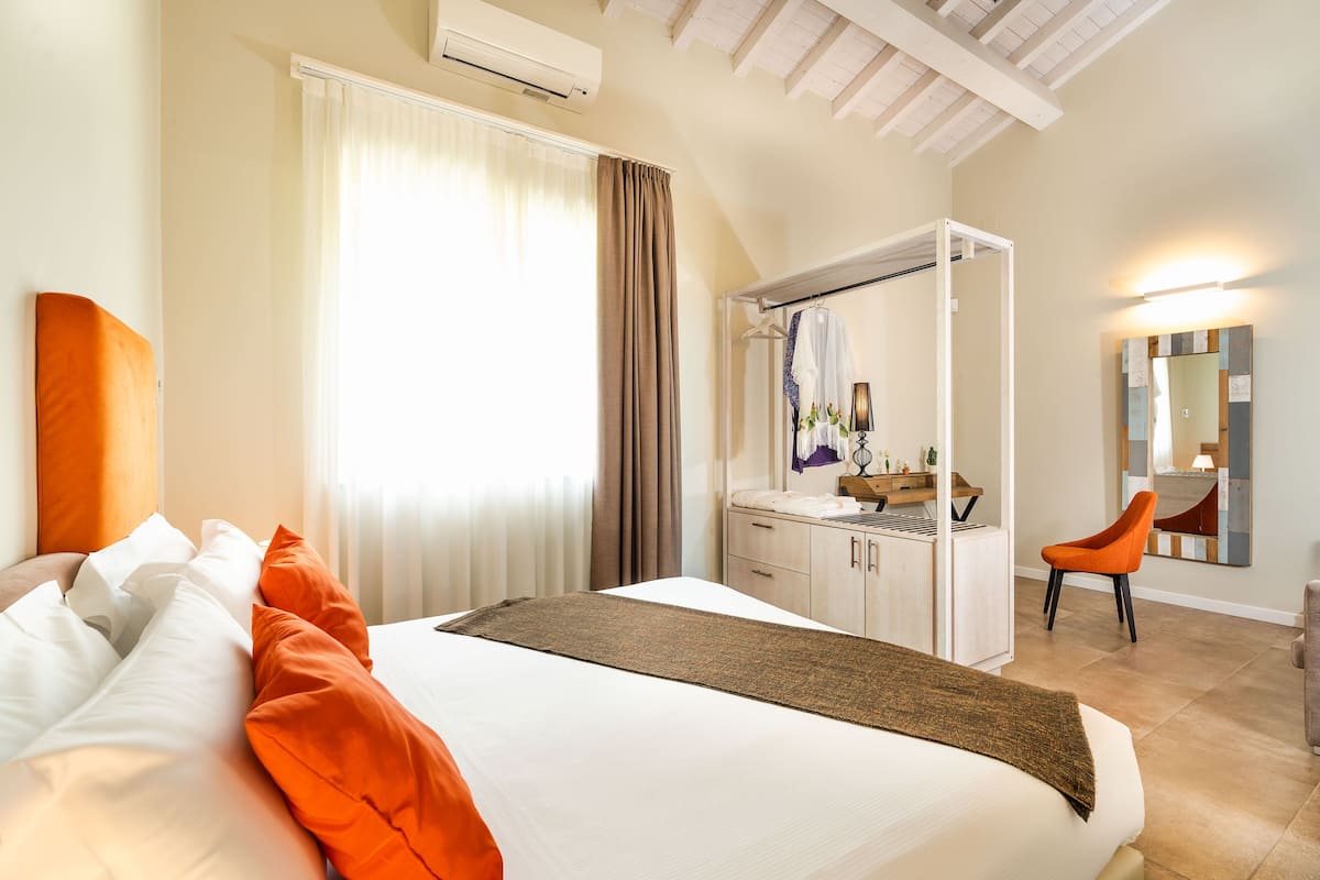 Une chambre d’hôtel avec un lit, une coiffeuse avec un miroir et une chaise.