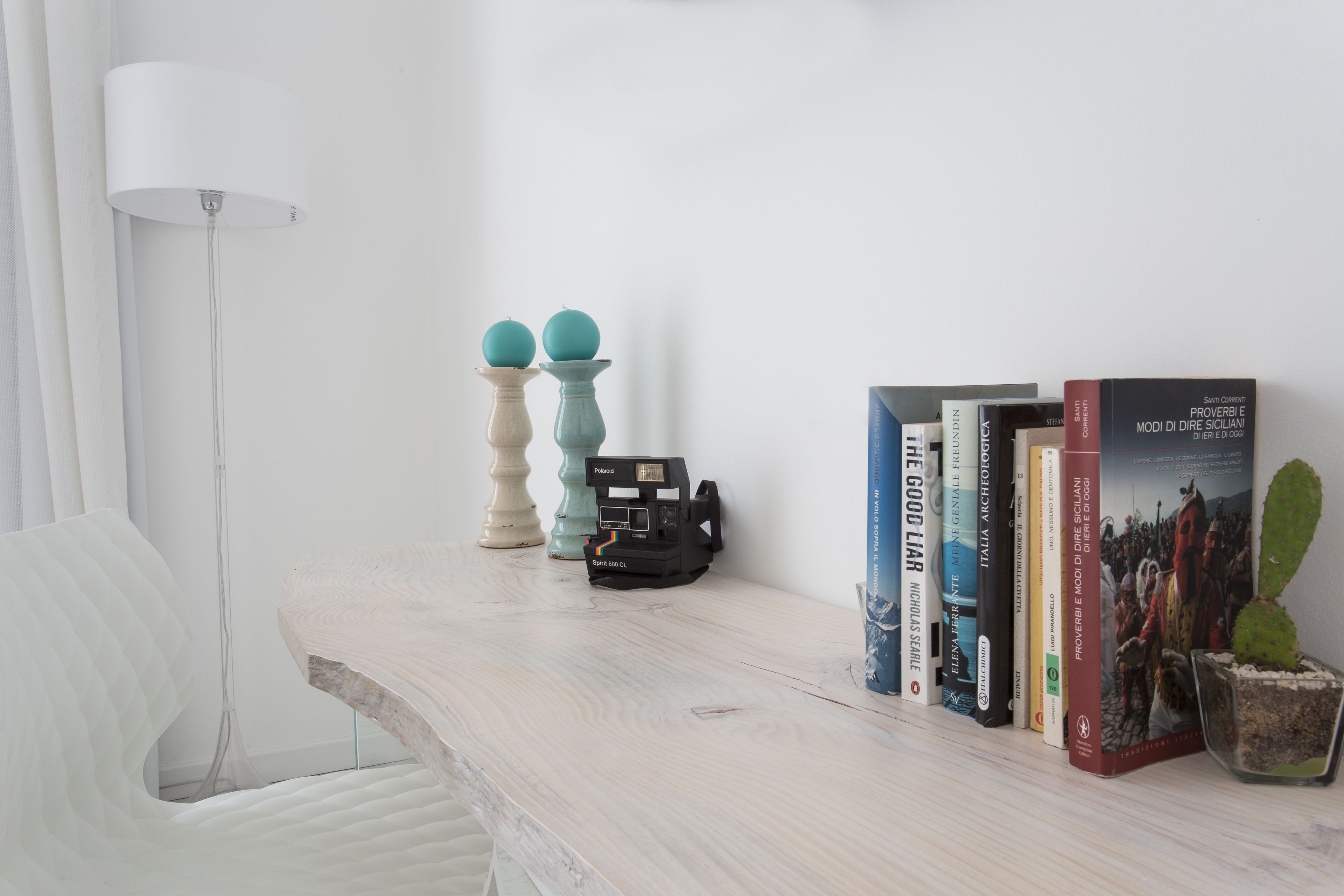 Un escritorio de madera con una lámpara, libros y un cactus.