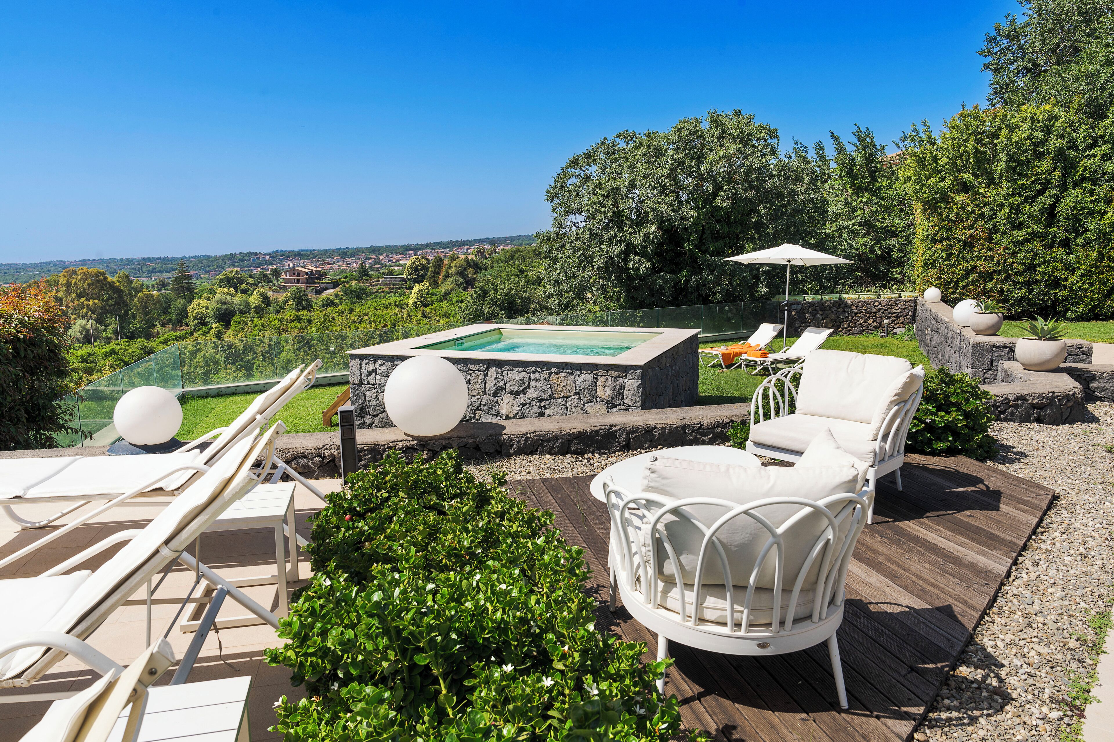 Un espace piscine sur le toit, avec des chaises longues, un jacuzzi et une vue panoramique.