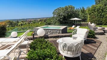Un espace piscine sur le toit, avec des chaises longues, un jacuzzi et une vue panoramique.