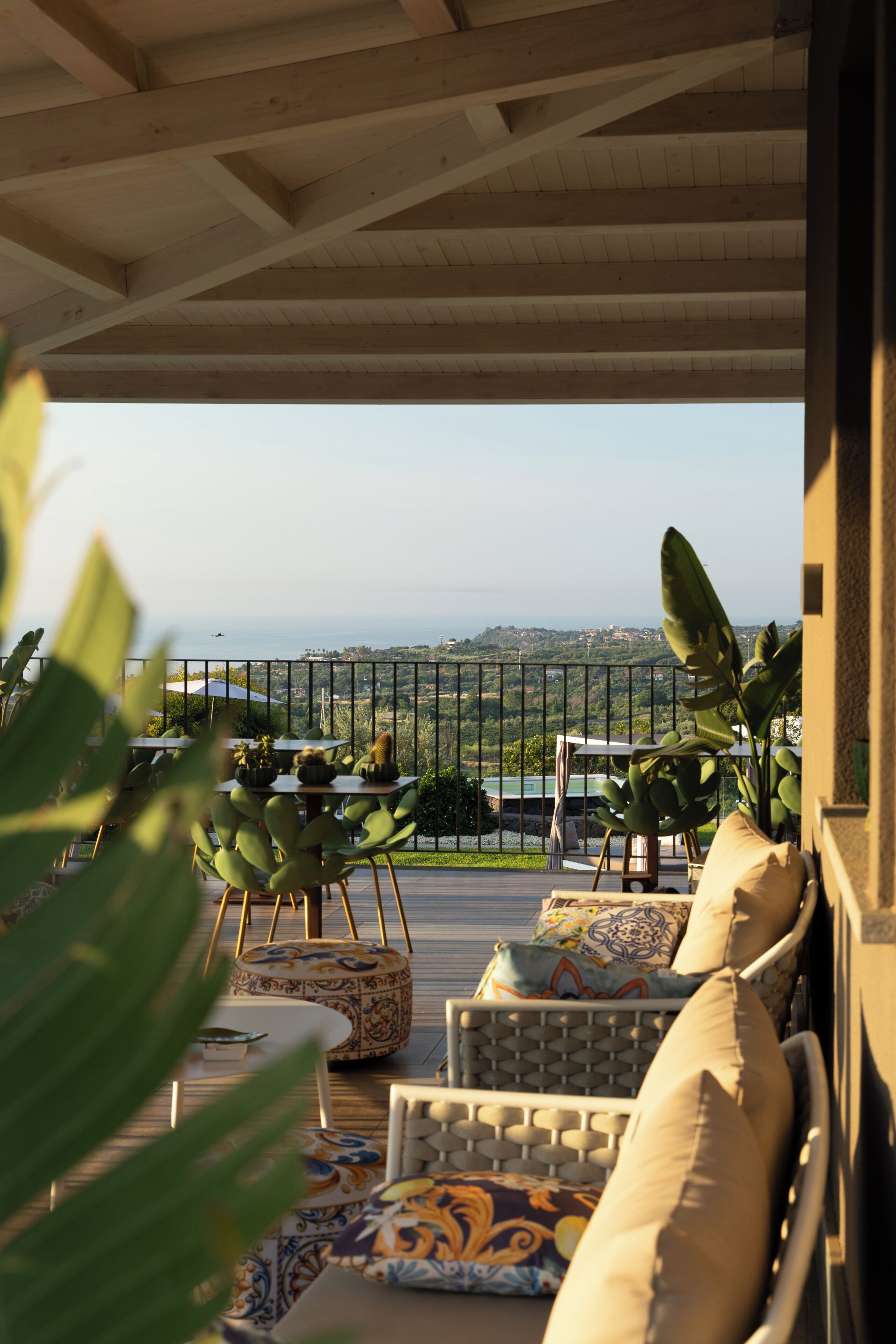 A terrace with outdoor seating, a view of the city, and a wooden ceiling structure.
