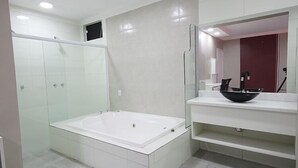 Un baño moderno con una bañera grande, cabina de ducha con mampara de vidrio y tocador con espejo y lavabo.