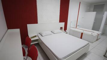 Un dormitorio moderno con una cama blanca, sillas rojas, un armario blanco y una pared texturizada en rojo y blanco.