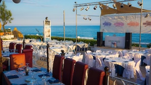 En restaurang vid havet med bord uppställda för servering, med utsikt över havet.