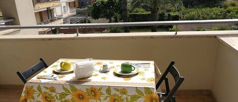Un balcón con una mesa dispuesta para dos, con mantel de girasoles.