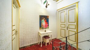 Un pasillo con un escritorio blanco, un cuadro y una alfombra roja.