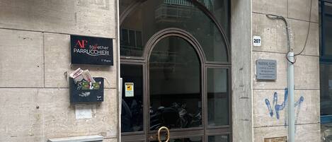 A building entrance with a glass door, a sign reading "AF to together PARRUCCIERI," and a "PANORAMIC ROOMS" sign.