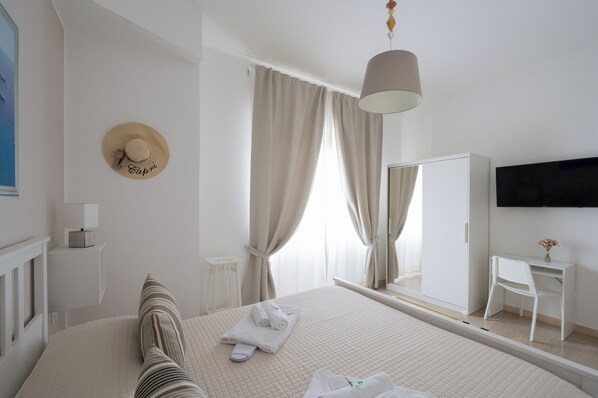 A hotel room with a bed, a bedside table, a mirror, a desk, and a TV mounted on the wall. - Panoramic Rooms Salerno (Salerno)