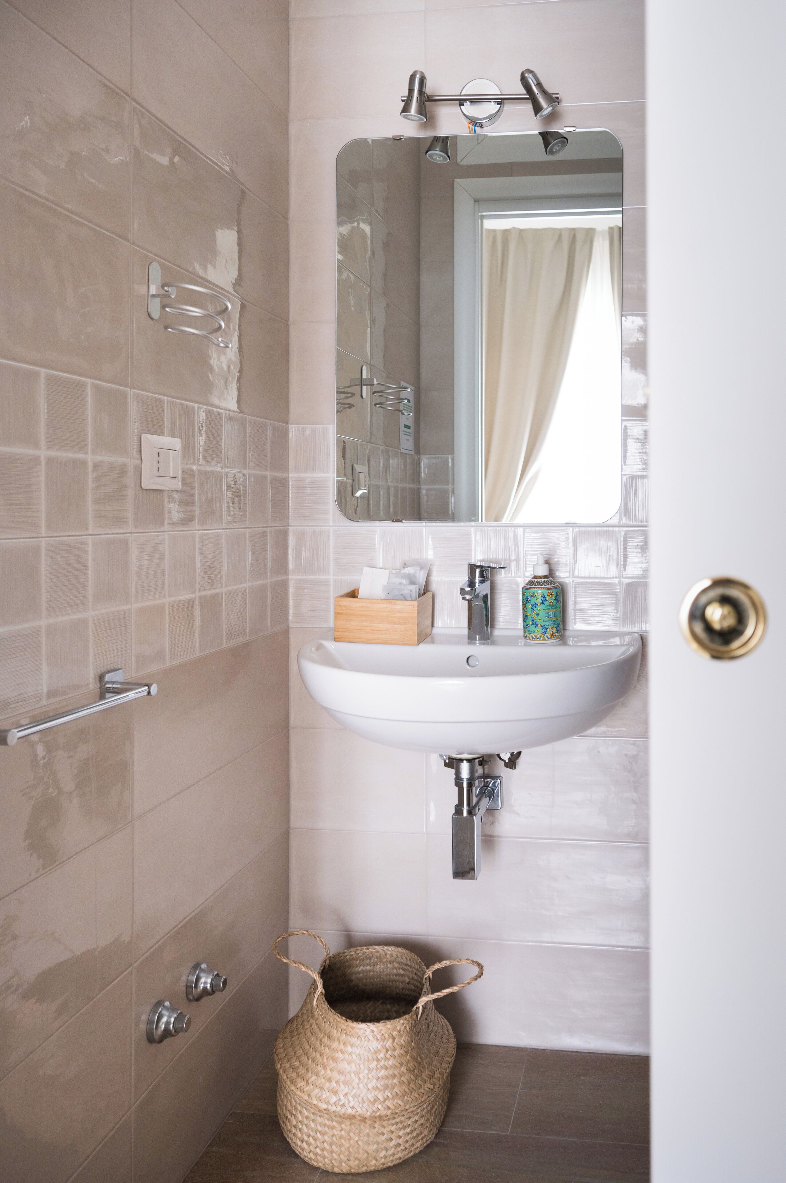 A bathroom with a white sink, mirror, and towel rack. There is a woven basket on the floor.