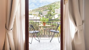 Een balkon met twee stoelen, een kleine tafel en een bloempot.