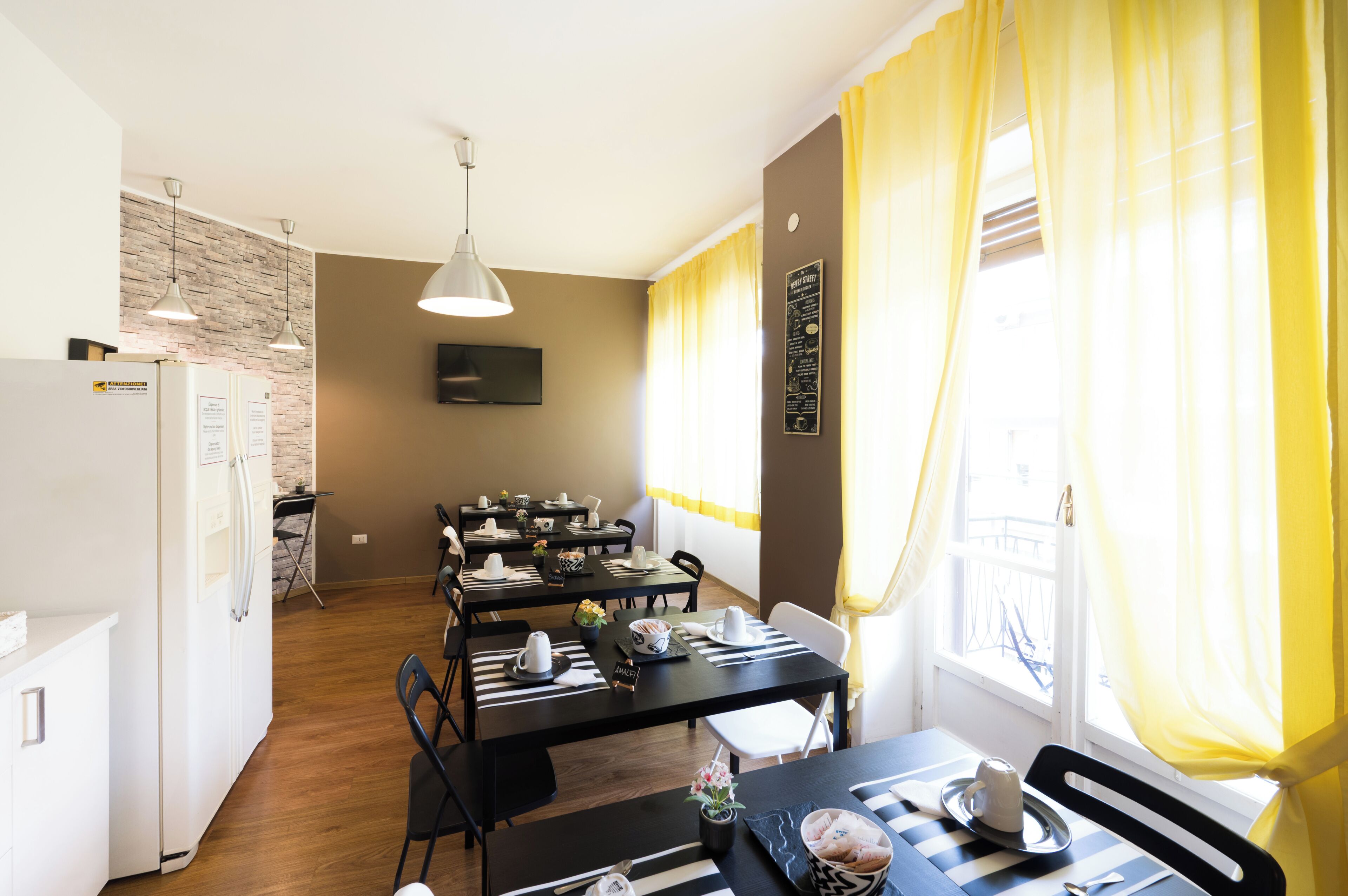 A dining area with tables, chairs, and a kitchen in the background.