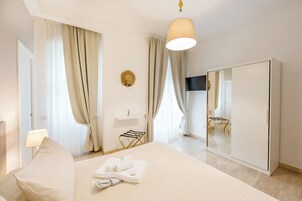 A hotel room with a bed, a wardrobe, a TV, and a window with curtains.