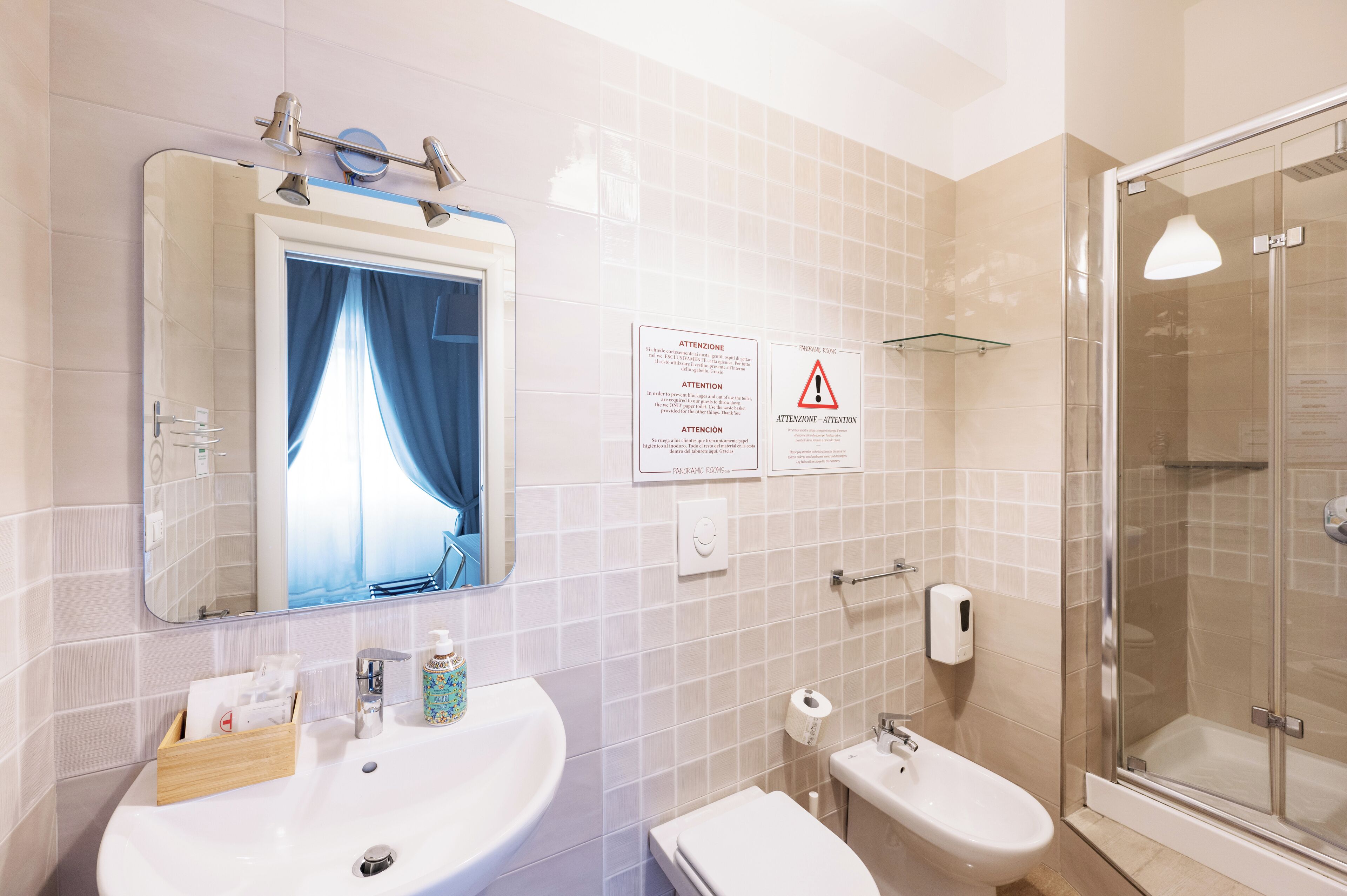 A bathroom with two sinks, a mirror, a shower, and safety signs.