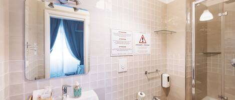 A bathroom with two sinks, a mirror, a shower, and safety signs.