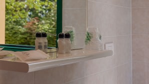 Ein Badezimmer mit Spiegel, Ablagefläche für Toilettenartikel und Fenster mit Blick auf Bäume.