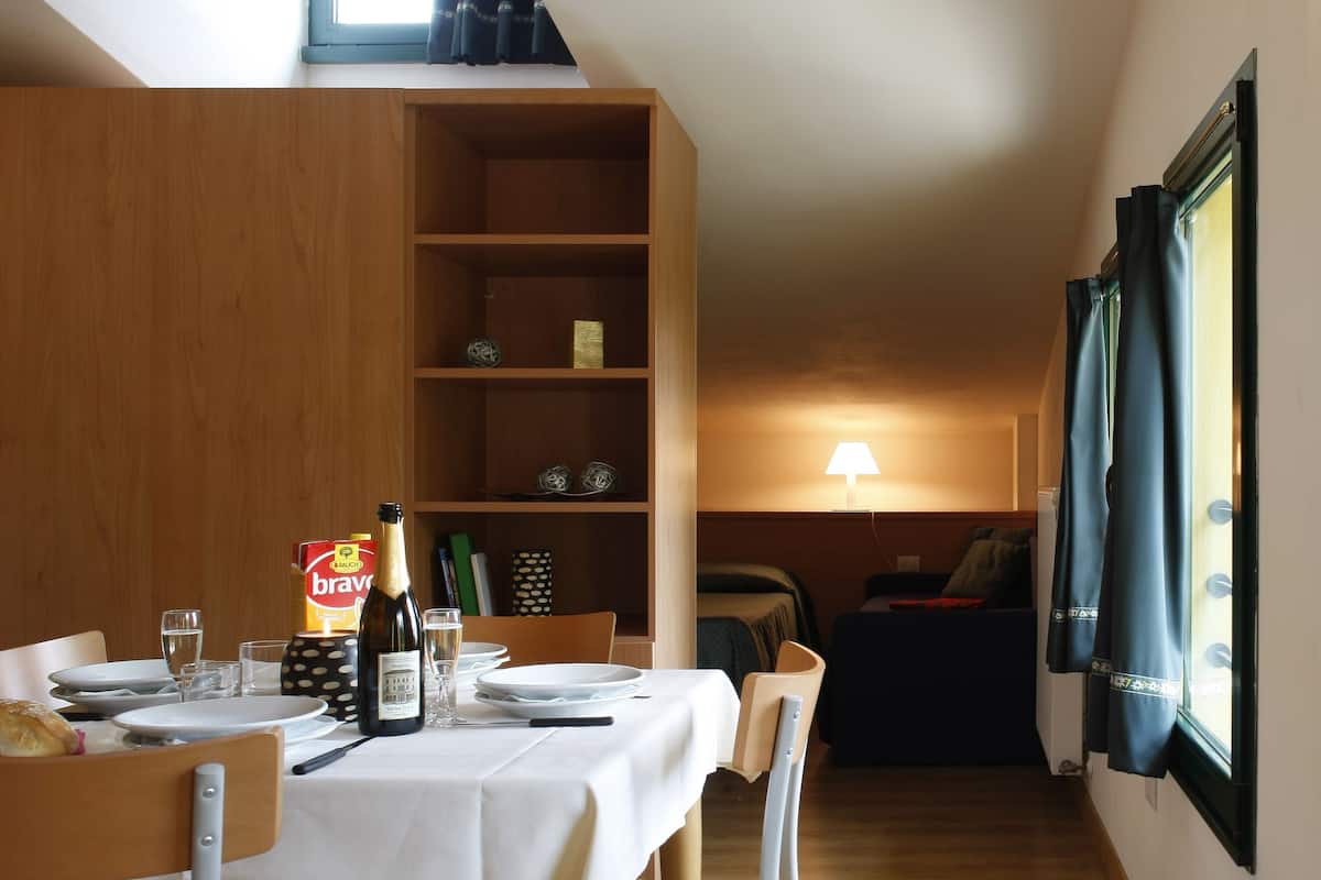 Un coin repas avec une table dressée pour deux personnes, une bouteille de champagne et une bibliothèque en arrière-plan.