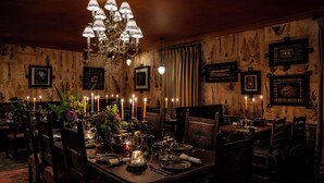 A formal dining room with a chandelier, candles, and framed botanical prints on the walls. - Loch Lomond Arms Hotel (Alexandria)