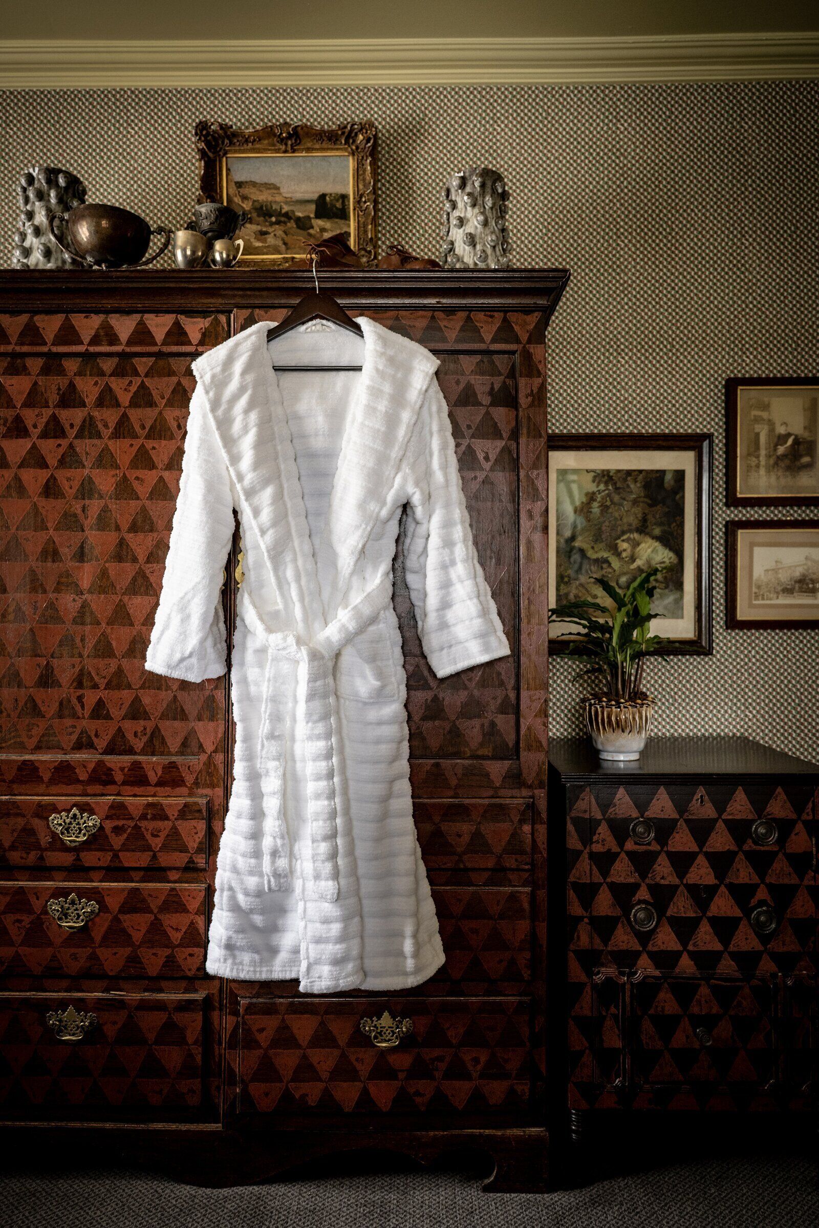 A white robe hanging on a wooden cabinet with a geometric pattern.