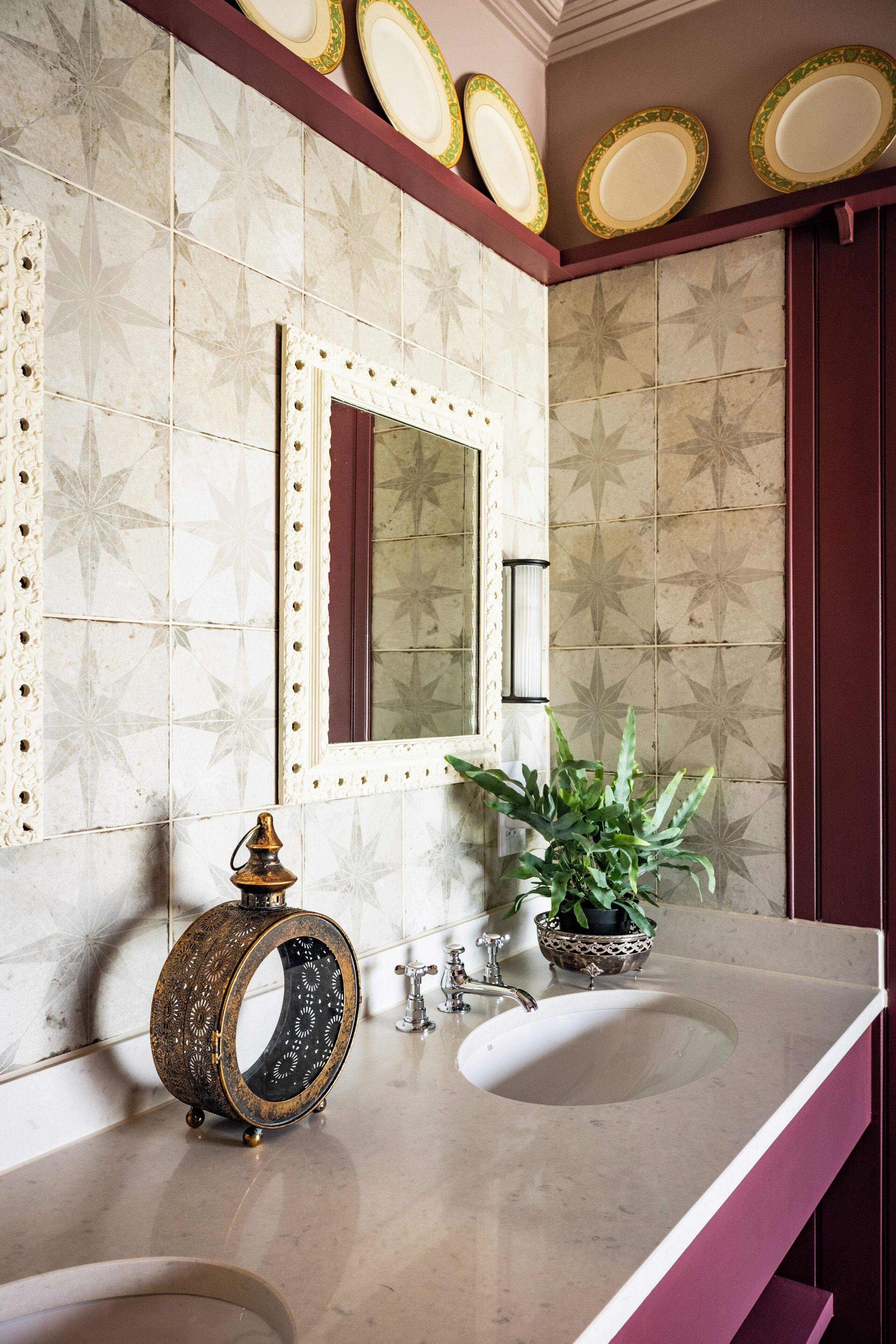 Une salle de bain avec deux lavabos, un miroir, des assiettes décoratives accrochées au mur et une plante en pot.