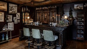 A bar area with wooden bar stools, a large mirror, and various barware. - Loch Lomond Arms Hotel (Alexandria)