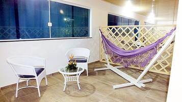 Relax in a serene space with a hammock, wicker chair, and a view of the night sky.