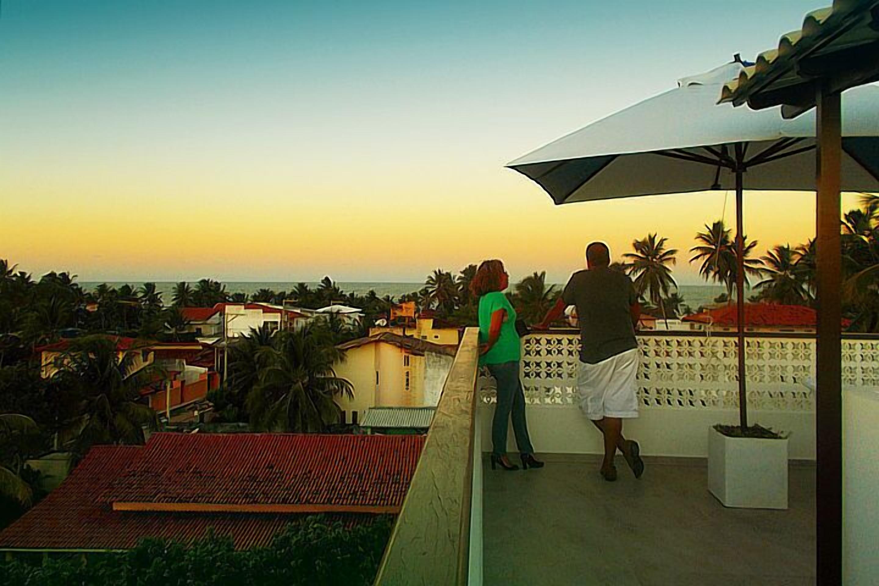 A balcony overlooking a coastal area with palm trees and buildings.