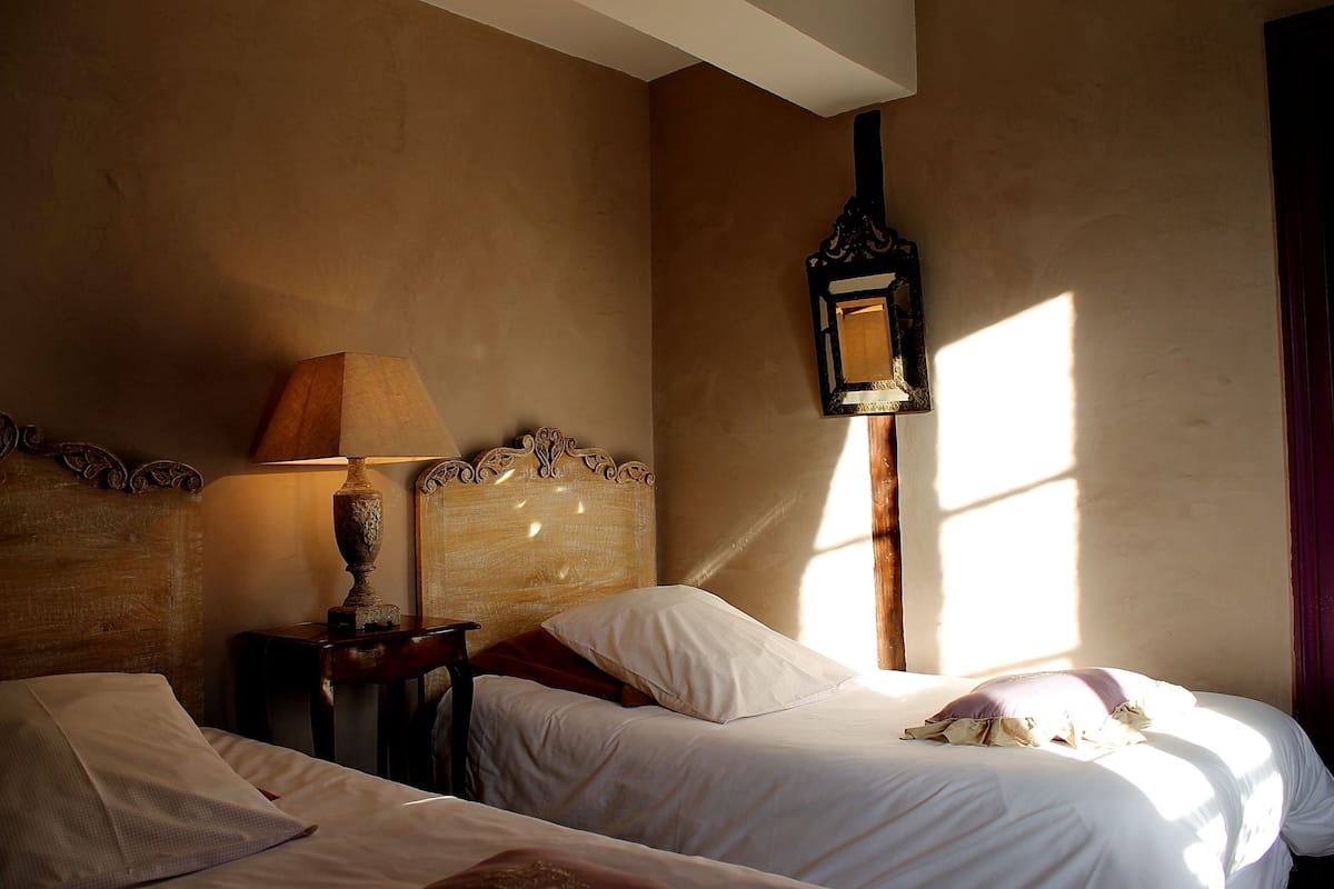 Une chambre d’hôtel avec deux lits, une tête de lit en bois, une lampe de chevet et un miroir fixé au mur.