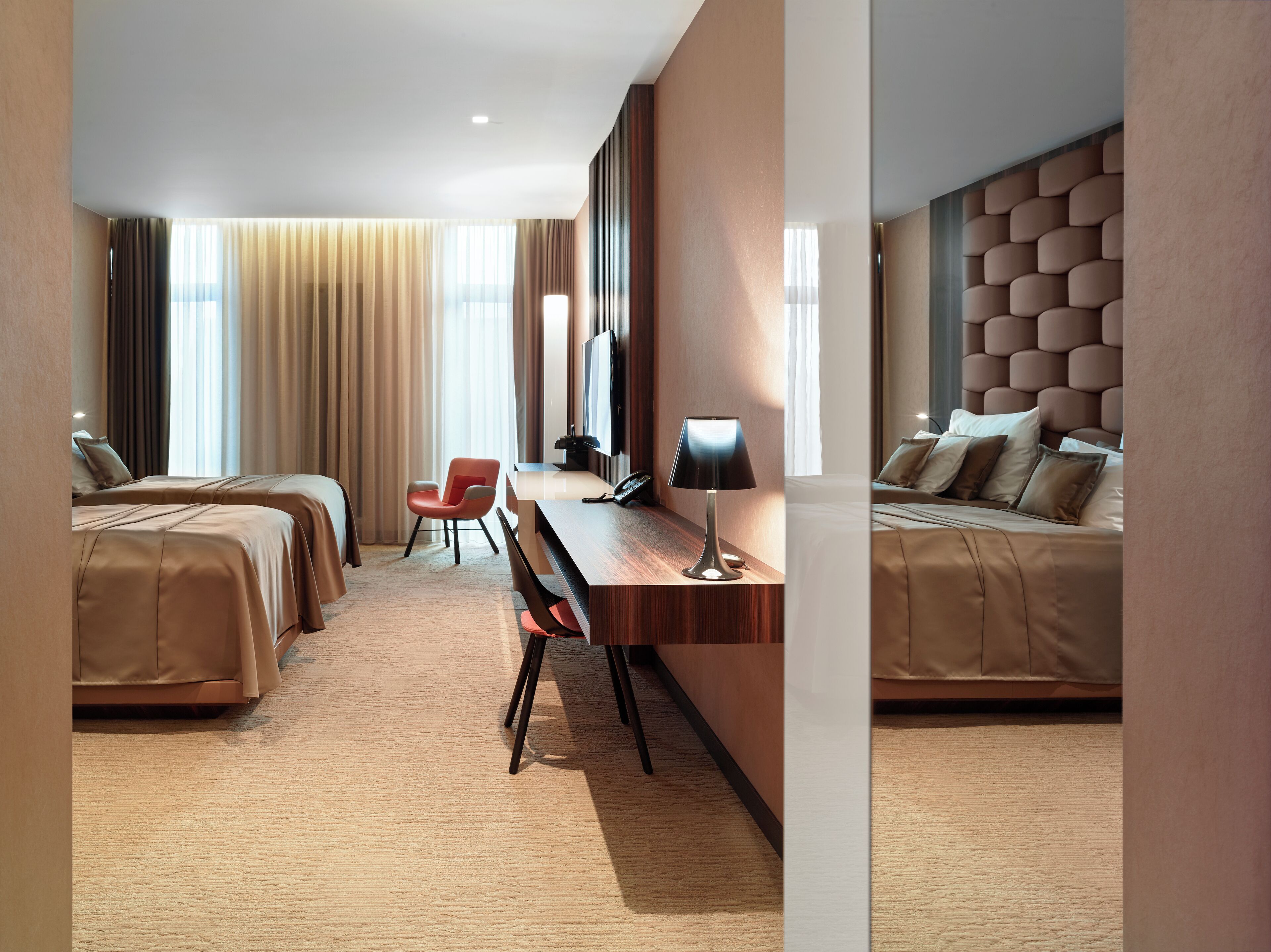 Une chambre d’hôtel avec deux lits, un bureau avec une lampe, une chaise et un téléviseur.