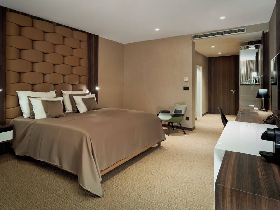 Ein modernes Hotelzimmer mit einem großen Bett, einem Schreibtisch und einem Sessel.