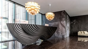 A modern lobby with a large sculptural bowl centerpiece, a sofa, and a mural on the wall. - Theatre Hotel (Olomouc)