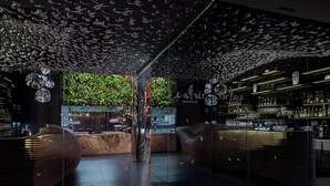 A modern bar with a unique ceiling design, a central column, and a glass partition. - Theatre Hotel (Olomouc)